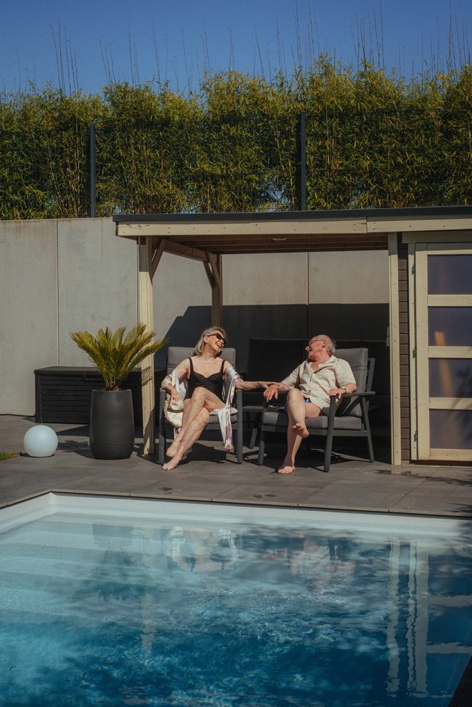 Ein älteres Ehepaar sitzt an einem Pool