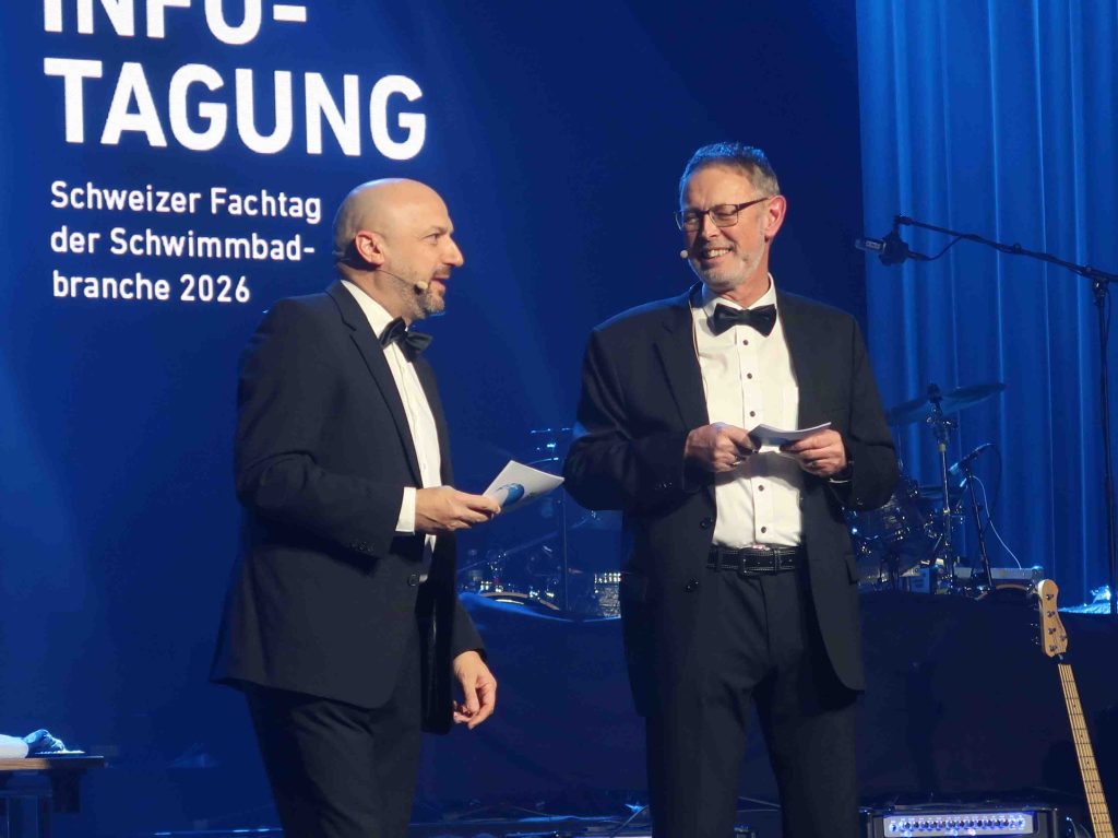 Die beiden Geschäftsführer Domenico Conte und Yves Burgener im schwarzen Anzug mit Fliege auf der Bühne bei der As Infotagung.