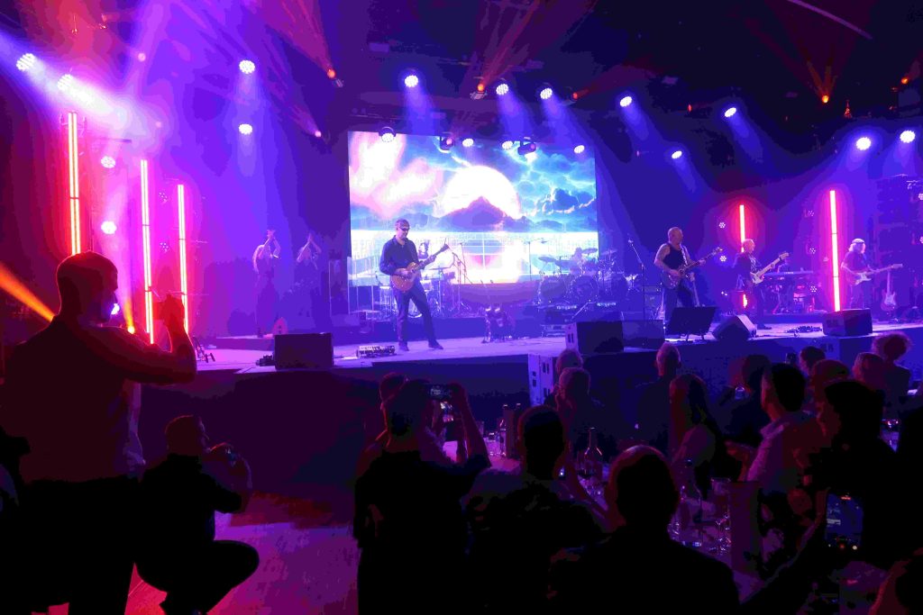 Die Rockband liefert eine Show auf der Bühne und das Publikum feiert.