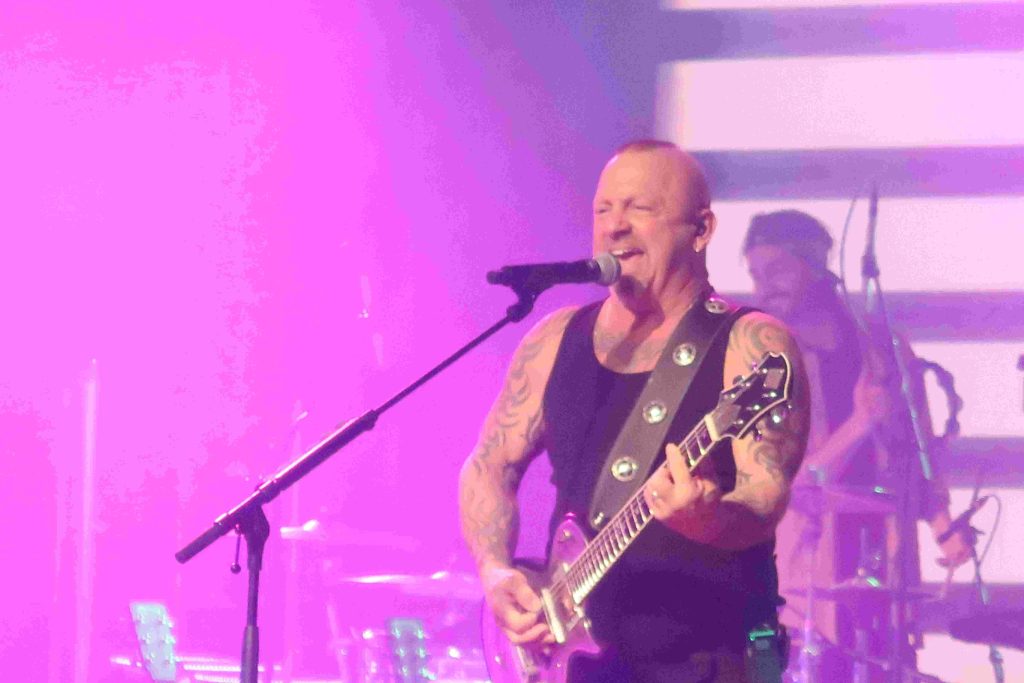 Die Rockband liefert eine Show auf der Bühne und das Publikum feiert.