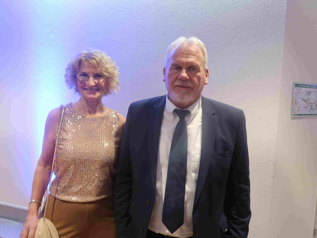 Frau in Paillettenoberteil und Mann in Anzug mit Krawatte.