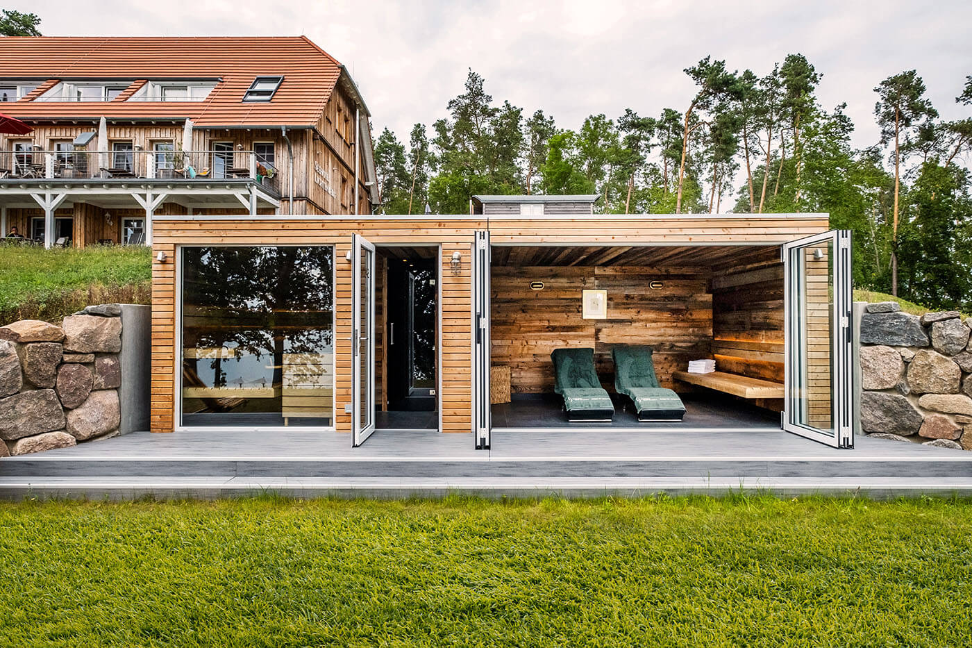 Gartensauna aus Holz mit Holzsteg auf dem Rasen