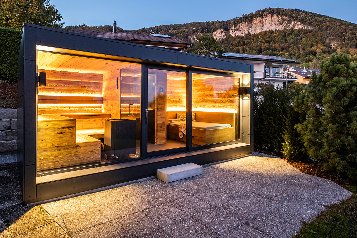 Gartensauna aus Holz mit Holzsteg auf dem Rasen