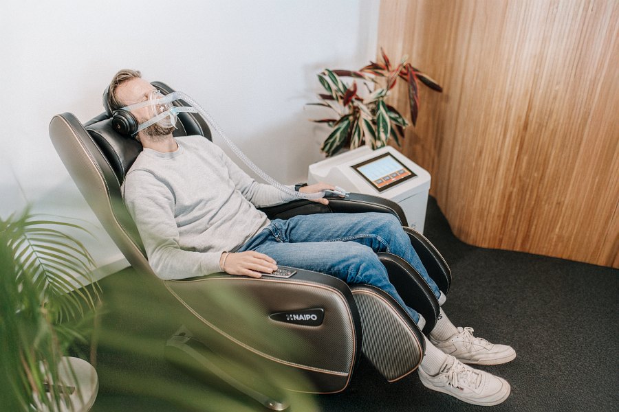 Ein Mann liegt mit einer Sauerstoffmaske auf einem bequemen Sessel.