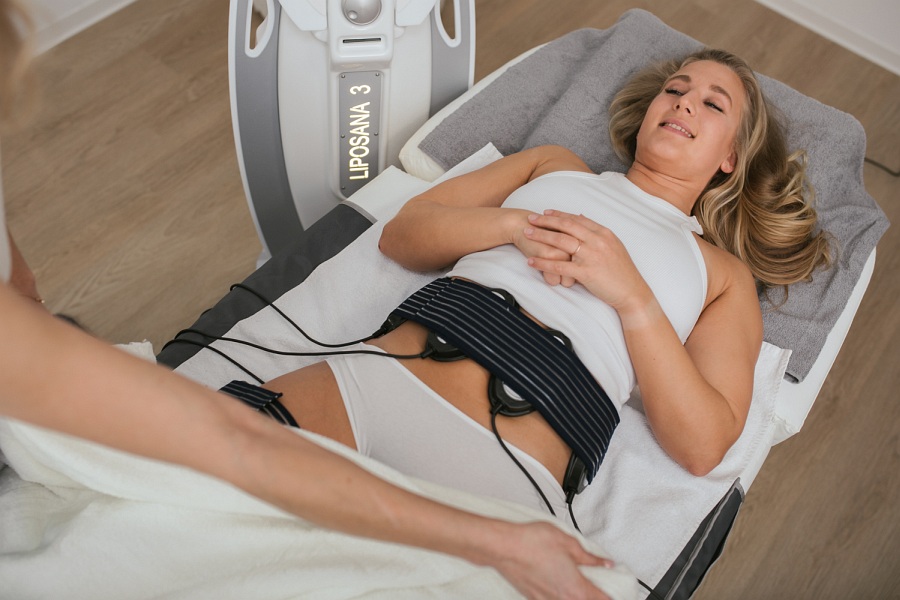 Eine Frau liegt auf einer Liege. An ihrem Bauch sind Elektroden angebracht.