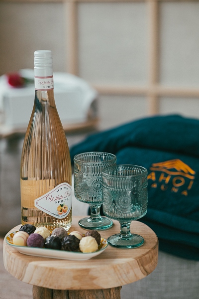 Detailaufnahme von Apfelsaft, Gläsern und Pralinen auf dem kleinen Holztisch.