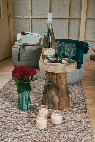 Apfelsaft, Gläser, Pralinen, Blumen und Kerzen stehen auf und neben einem kleinen Tisch im Vorraum der Sauna.