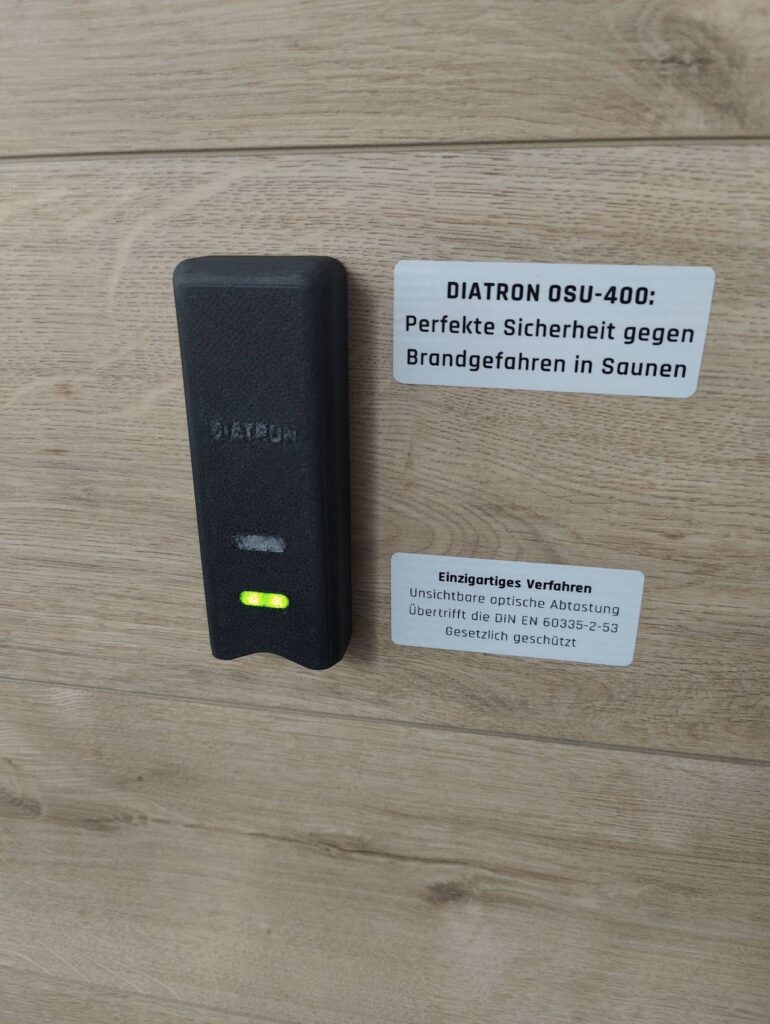 Die Ofenüberwachung in Form einer kleinen Box ist über dem Saunaofen an der Wand angebracht.
