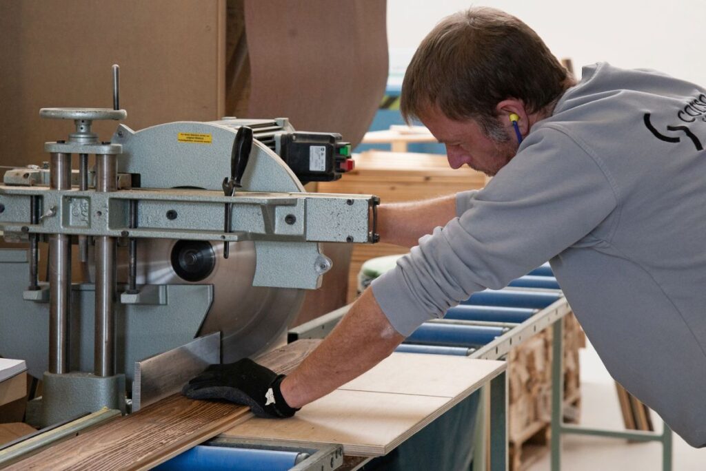 corso Sauna Arbeiter schneidet Holz mit Kreissäge zu