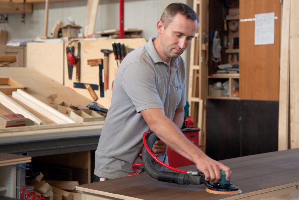 corso sauna Arbeiter in der Werkstatt schleift Holz mit Maschine